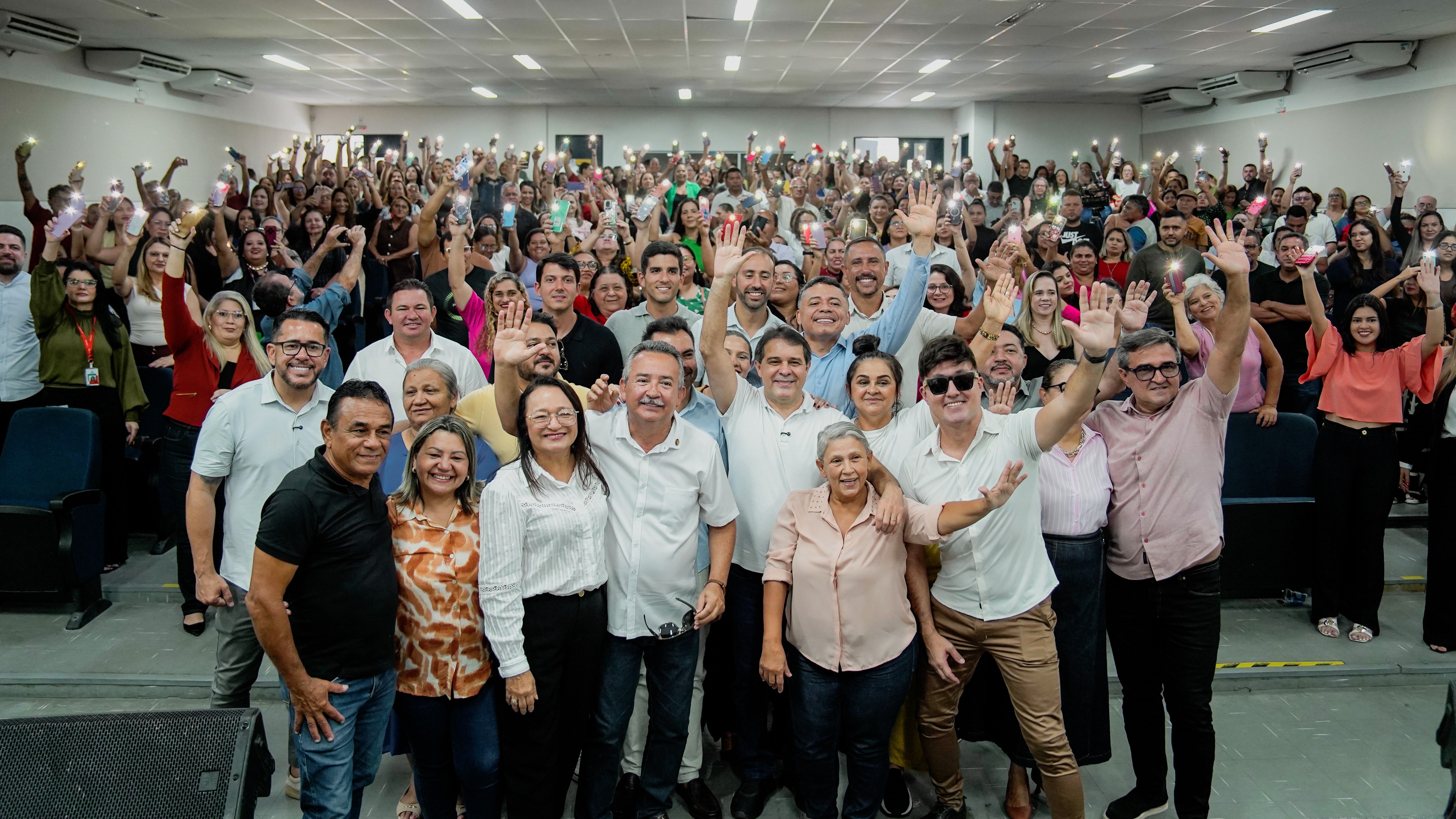 grupo de pessoas posa para a foto no auditório da SME